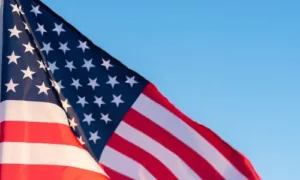 Close-up of the American flag waving against a clear blue sky.